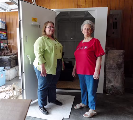 Betty and Linda Harryman show off the safe room they installed in the garage of their new home following last year's tornado in Joplin, Mo.